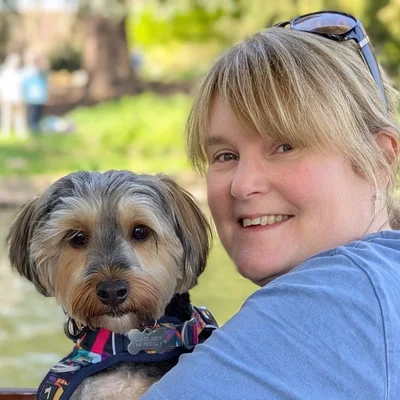 Nicky Youngman smiling, with Ziggy the dog, on a day trip to Stratford-upon-Avon